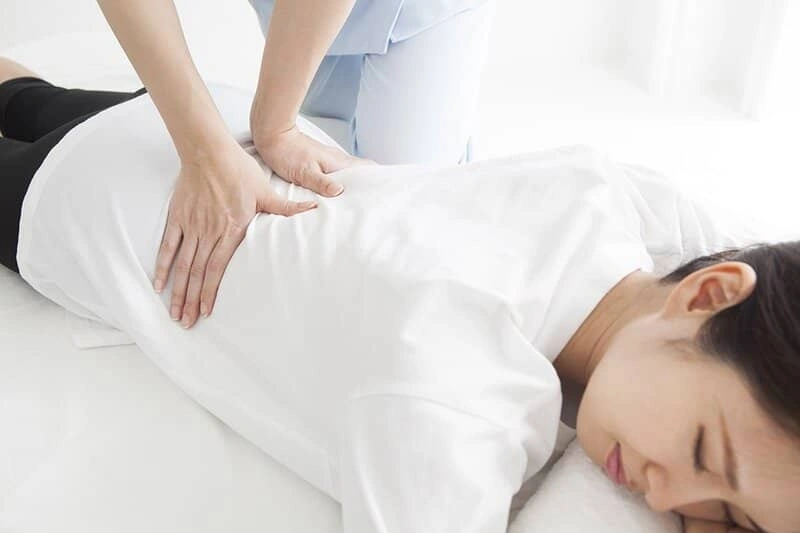 A woman having her lower back treated by a chiropractor.