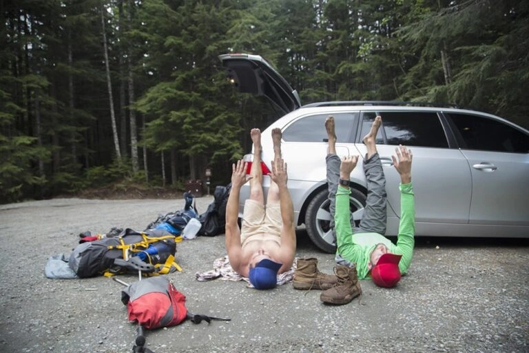 hikers-stretching-beside-vehicle-in-forest-lake