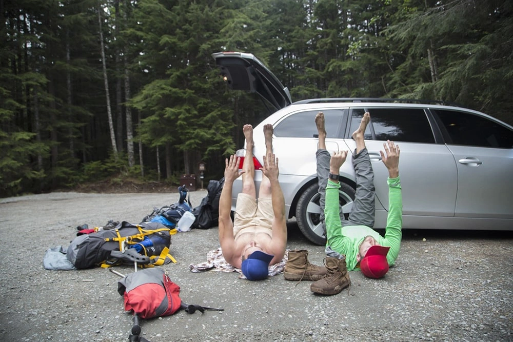 hikers-stretching-beside-vehicle-in-forest-lake