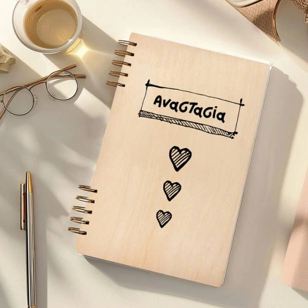 Ξύλινη ατζέντα με σπιράλ και όνομα «Αναστασία» στο εξώφυλλο, σχέδιο με καρδιές, πάνω σε γραφείο με στυλό, γυαλιά και φλιτζάνι.
        loading=