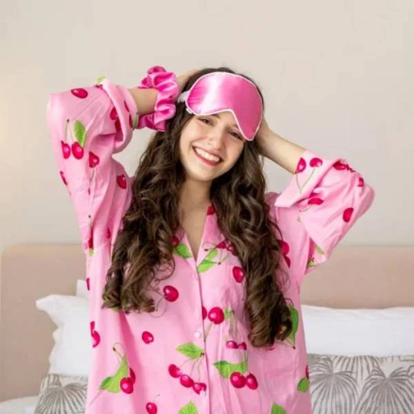 Χαμογελαστή κοπέλα με ροζ σατέν μάσκα ύπνου και πιτζάμες με κεράσια σε φωτεινό υπνοδωμάτιο.
        loading=