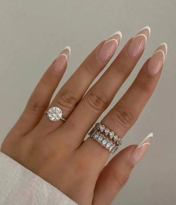 Νυφικά νύχια με γαλλικό μανικιούρ και δύο δαχτυλίδια, ένα μονόπετρο και ένα eternity ring με διαμάντια.