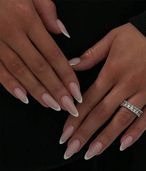 Νυφικά νύχια με γαλλικό μανικιούρ σε αμυγδαλωτό σχήμα, με λεπτή λευκή γραμμή και ένα ασημένιο δαχτυλίδι με διαμάντια.