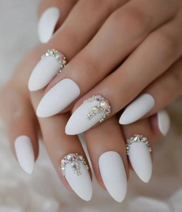 Νυφικά νύχια με ματ λευκό χρώμα και στρας, σε αμυγδαλωτό σχήμα.