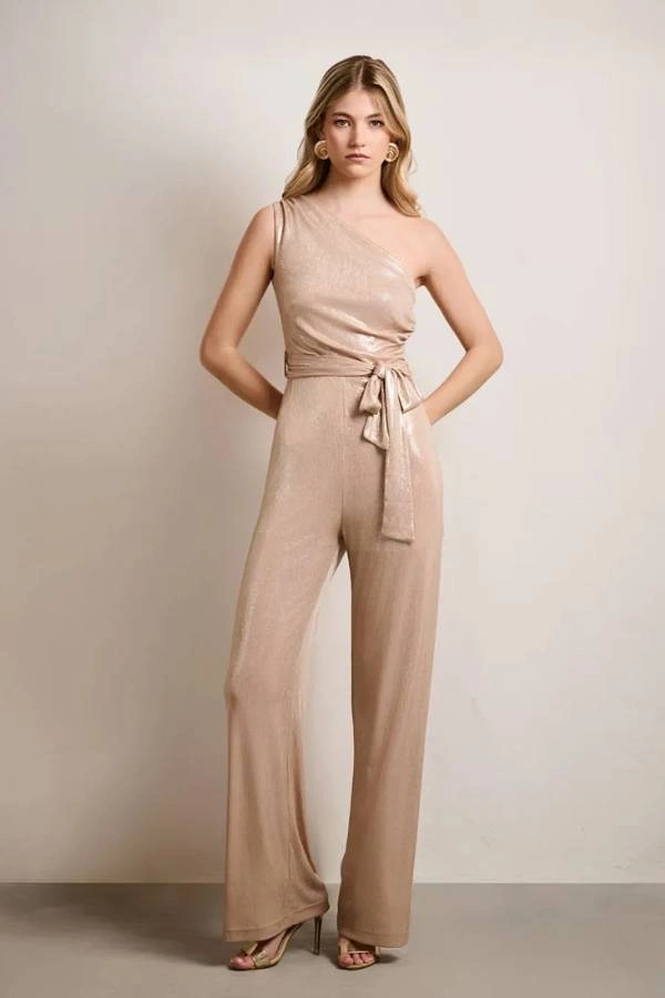 Ολόσωμη φόρμα σε χρυσή μεταλλιζέ απόχρωση με ασύμμετρη λαιμόκοψη και έναν ώμο, ελαστικό ύφασμα, ίσιο μπατζάκι και ασορτί ζώνη στη μέση, εφαρμοστή.