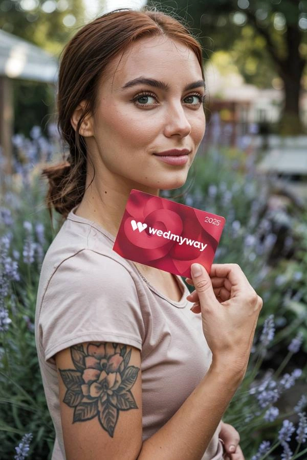 Όμορφη καοπέλα με τατουάζ στον ώμο κρατάει κάρτα του wedmyway