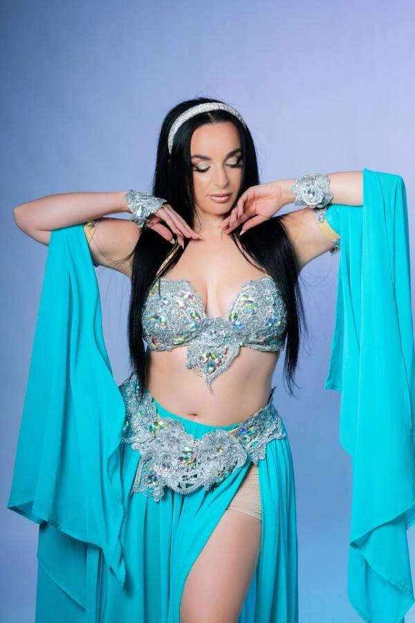 Η Ευδοκία Durrah, χορεύτρια Oriental, ποζάρει με κομψότητα, φορώντας ένα μπλε-τιρκουάζ και ασημί κουστούμι χορού.