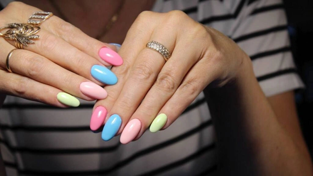 Γυναικεία χέρια με ημιμόνιμο μανικιούρ σε παστέλ αποχρώσεις ροζ, γαλάζιου και λάιμ