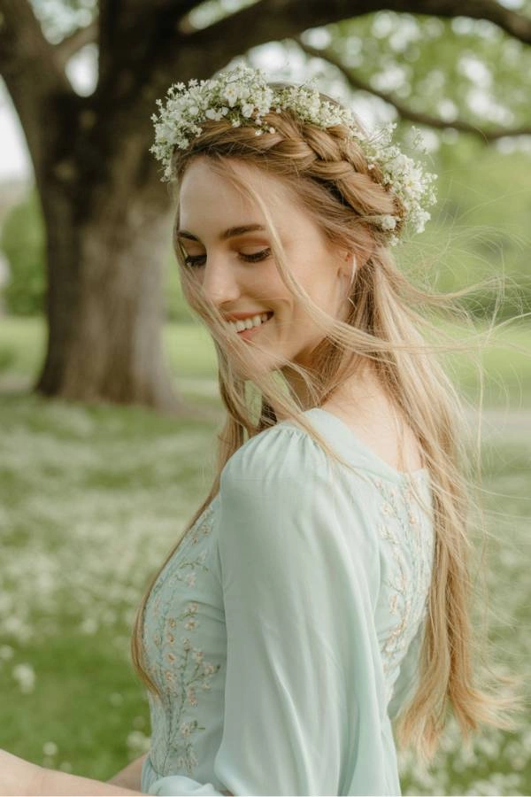 Κουμπάρα με crown braid και ανάλαφρο φόρεμα, σε ανοιξιάτικο εξωτερικό γάμο.