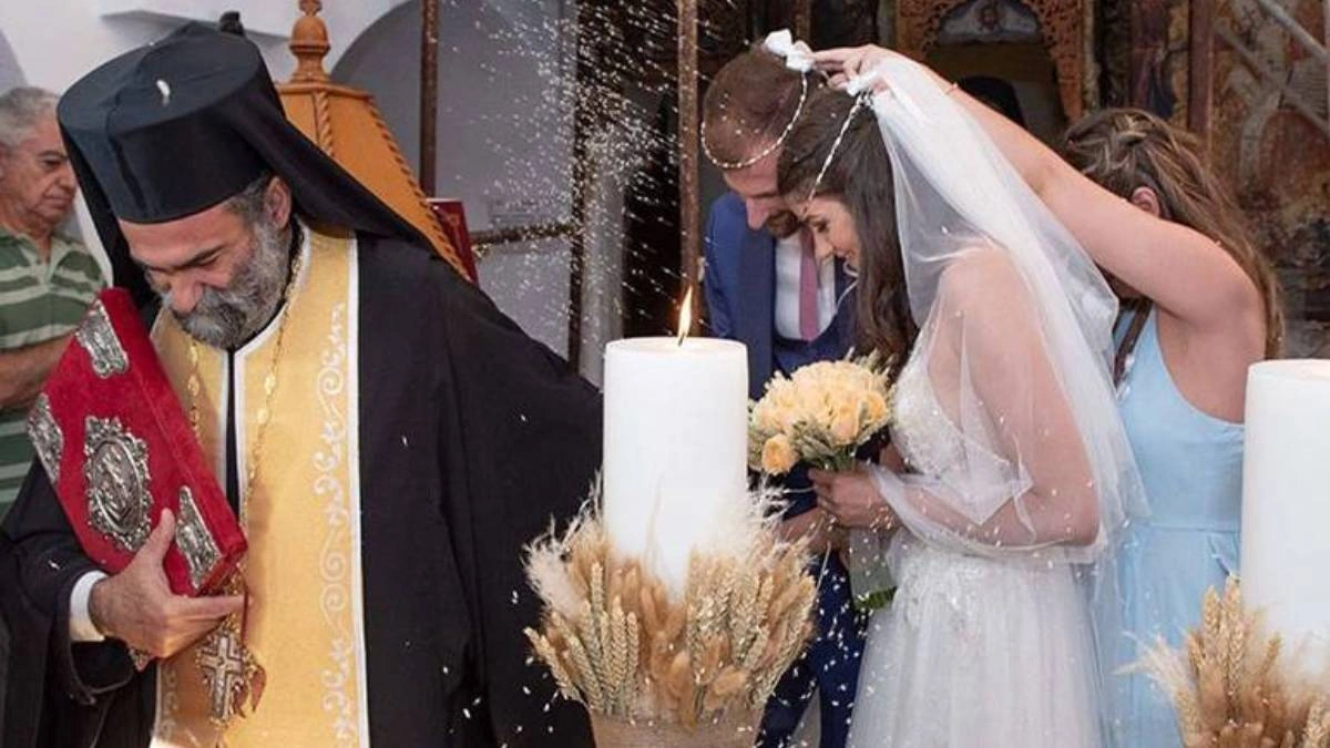 Η κουμπάρα αλλάζει τα στέφανα σε παραδοσιακό ελληνικό γάμο, δίπλα σε λαμπάδες και ιερέα – έξοδα και υποχρεώσεις κουμπάρου