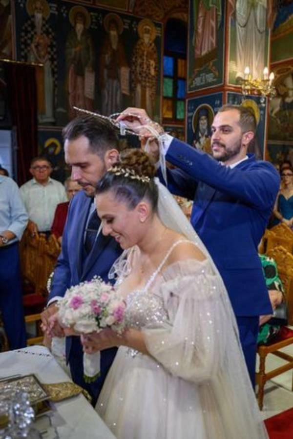 Ο κουμπάρος φοράει τα στέφανα στο ζευγάρι την ώρα του μυστηρίου μέσα σε εκκλησία