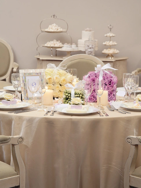 Ρομαντικός στολισμός γαμήλιου τραπεζιού με λευκά και λιλά τριαντάφυλλα και elegant λεπτομέρειες, από τη Vassiliki Creations