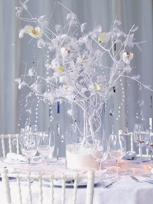Εντυπωσιακή λευκή διακόσμηση γαμήλιου τραπεζιού με centerpiece από λευκά κλαδιά, ορχιδέες και κρυστάλλινες λεπτομέρειες, από τη Vassiliki Creations