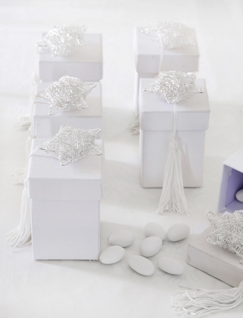 Λευκές μπομπονιέρες γάμου σε κουτάκια με ασημένια αστέρια και λευκή φούντα, τοποθετημένες σε elegant τραπέζι δεξίωσης, από τη Vassiliki Creations στο King George