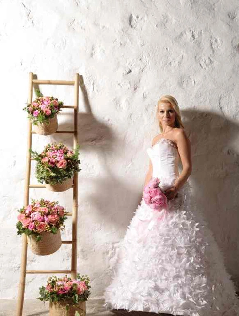 Νύφη με λευκό νυφικό σε ρομαντική σύνθεση με ροζ λουλούδια σε καλάθια και ξύλινη σκάλα, διακόσμηση από τη Vassiliki Creations στο Grand Resort