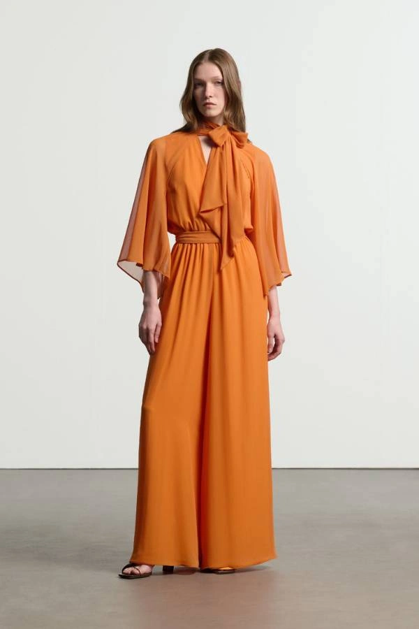 Πορτοκαλί jumpsuit με αέρινα μανίκια και φιόγκο στο λαιμό, κομψή εναλλακτική επιλογή για κουμπάρα