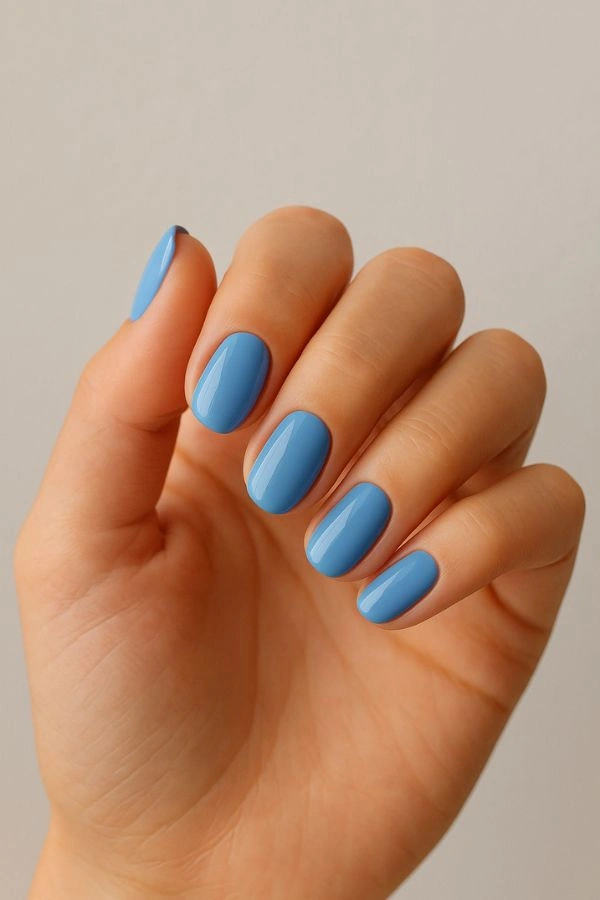 Κοντινό σε χέρι καλεσμένης με παστέλ μπλε γυαλιστερό μανικιούρ σε ουδέτερο φόντο, κομψή ιδέα για νύχια για γάμο.