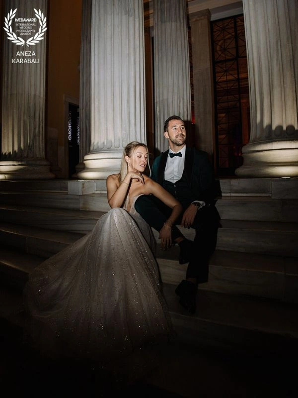 Νυχτερινό πορτρέτο ζευγαριού σε σκαλιά νεοκλασικού κτιρίου στην Αθήνα