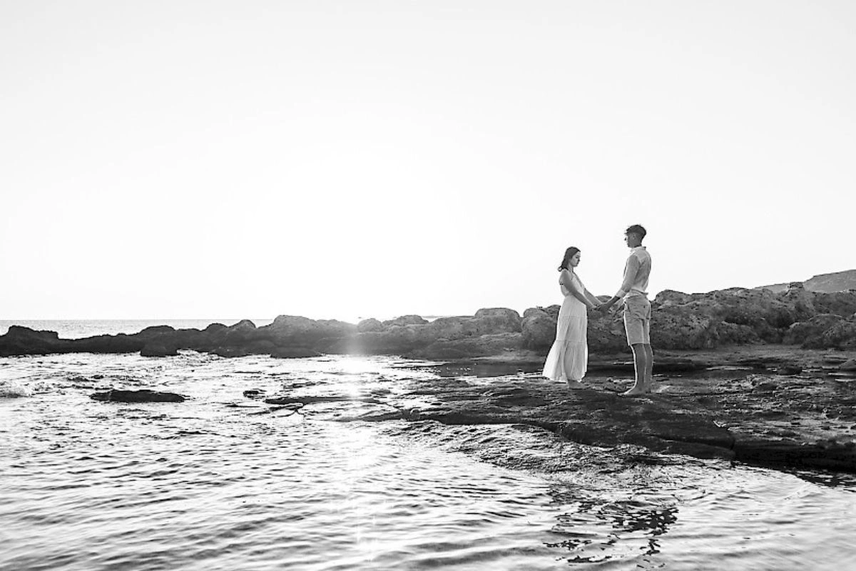 Ζευγάρι κρατιέται χέρι χέρι σε βραχώδη ακτή κατά τη φωτογράφιση γάμου