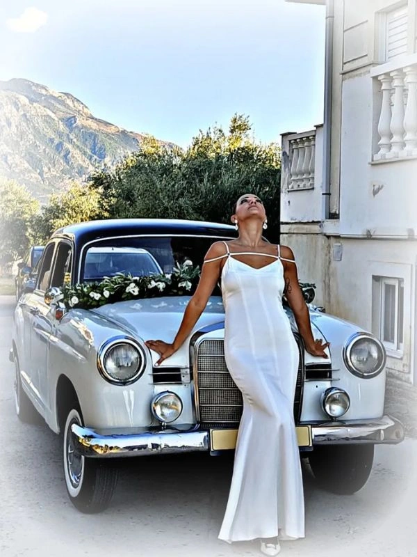 Νύφη μπροστά από κλασικό αυτοκίνητο γάμου Mercedes σε ρομαντικό σκηνικό
