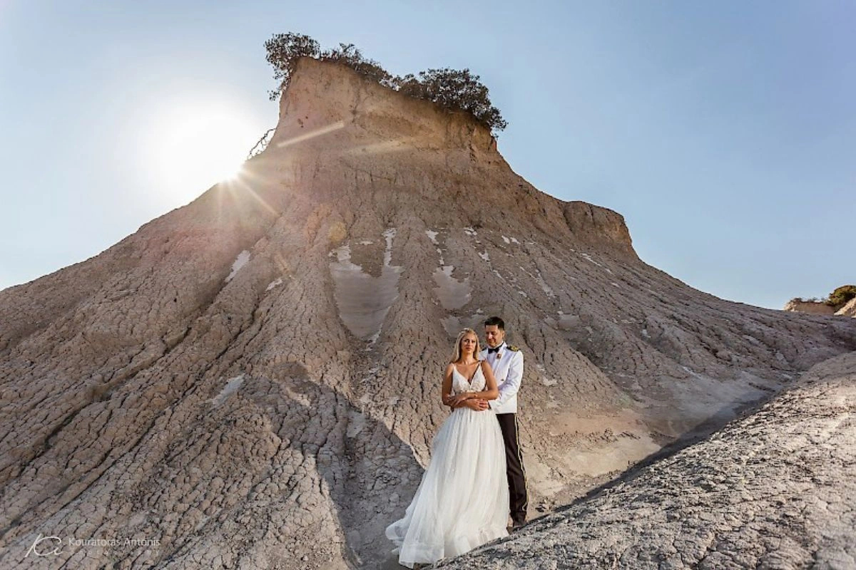 Νύφη και γαμπρός αγκαλιασμένοι σε εντυπωσιακό φυσικό τοπίο κατά τη φωτογράφιση γάμου