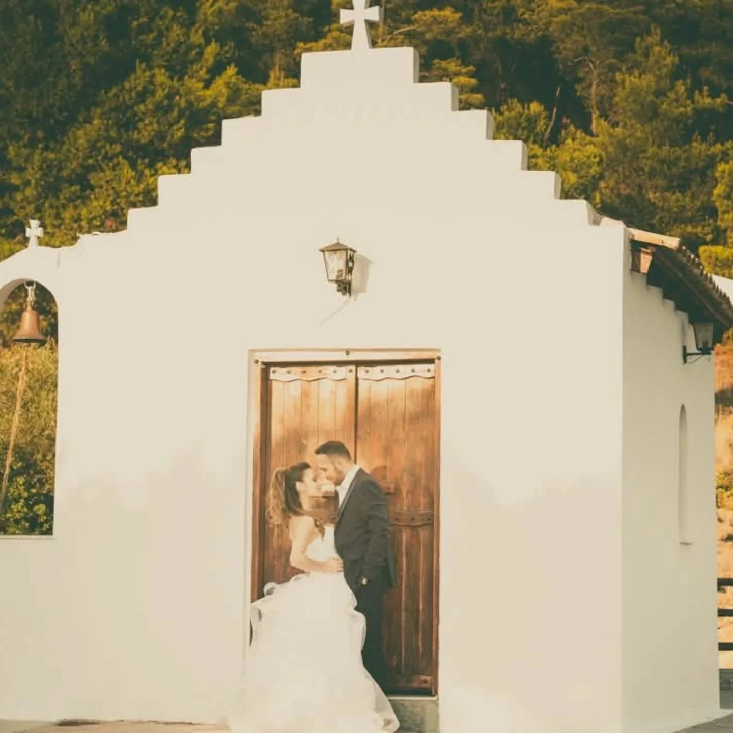 Ζευγάρι μπροστά σε λευκό εκκλησάκι σε ρομαντική φωτογράφιση γάμου από την Wedding Stars