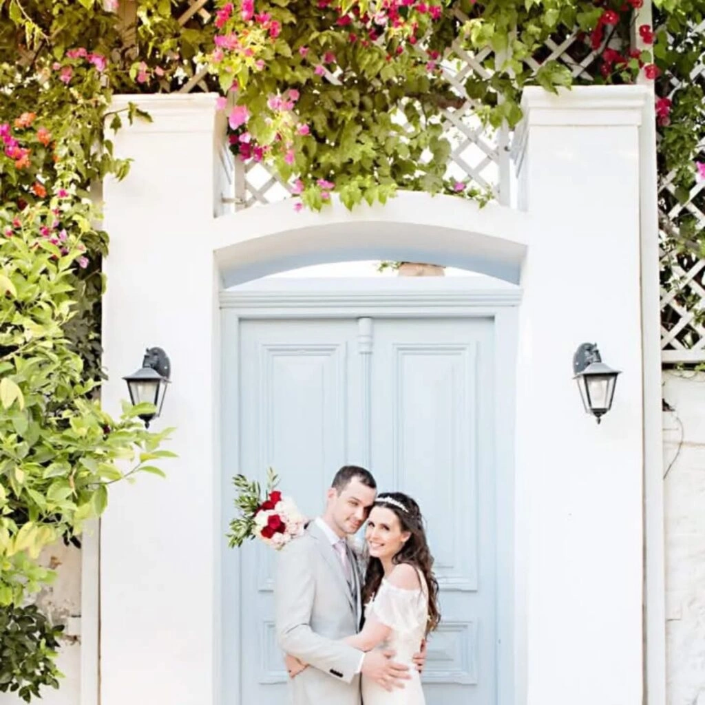 Ζευγάρι μπροστά σε ρομαντική πόρτα με λουλούδια σε φωτογράφιση γάμου από την Wedding Stars