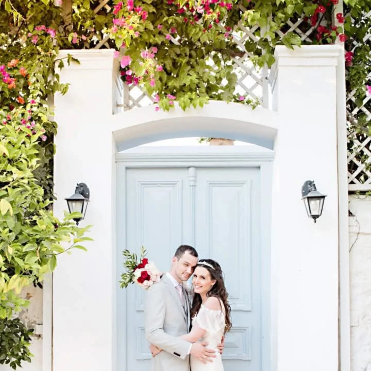 Ζευγάρι μπροστά σε ρομαντική πόρτα με λουλούδια σε φωτογράφιση γάμου από την Wedding Stars